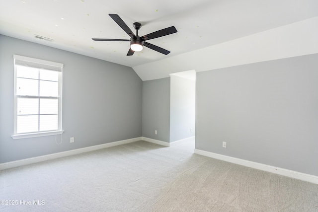 spare room featuring light colored carpet, baseboards, ceiling fan, and lofted ceiling