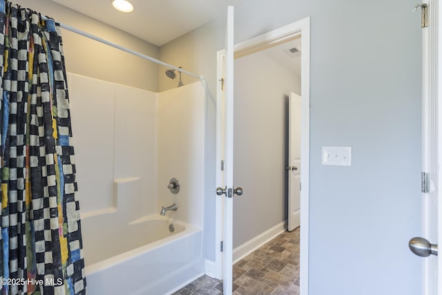 bathroom with stone finish floors, baseboards, shower / bath combo, and recessed lighting