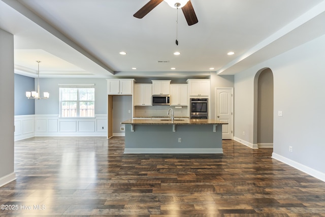 kitchen with stainless steel appliances, a center island with sink, white cabinets, a breakfast bar area, and a ceiling fan