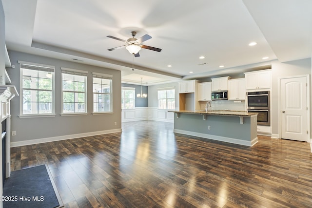 unfurnished living room with dark wood-style floors, a sink, a ceiling fan, a fireplace, and recessed lighting
