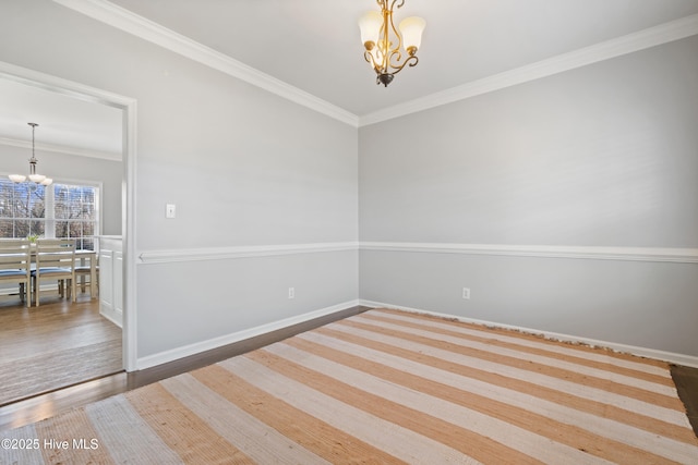 empty room with crown molding, baseboards, and a notable chandelier