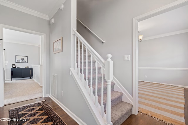 stairway featuring baseboards, crown molding, and wood finished floors