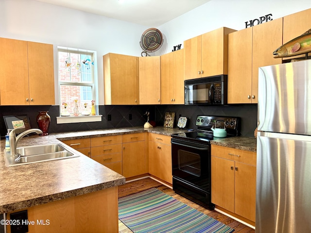 kitchen featuring black appliances, a sink, wood finished floors, and backsplash