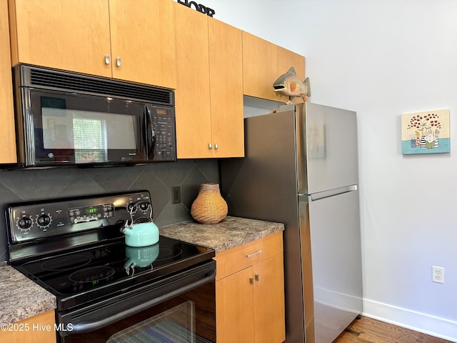 kitchen featuring black appliances, decorative backsplash, baseboards, wood finished floors, and light countertops