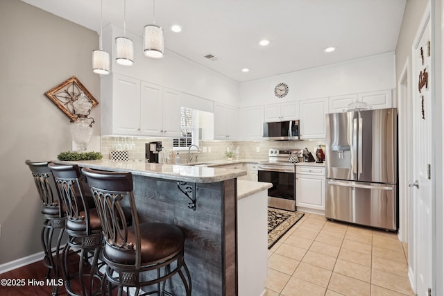 417 Pennington Loop, Myrtle Beach, SC 29588 - kitchen with appliances with stainless steel finishes, a peninsula, a kitchen breakfast bar, white cabinetry, and backsplash