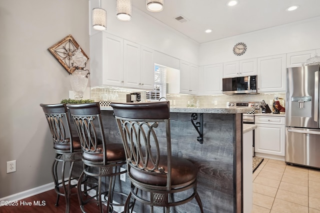 417 Pennington Loop, Myrtle Beach, SC 29588 - kitchen featuring appliances with stainless steel finishes, a kitchen breakfast bar, white cabinets, tasteful backsplash, and a peninsula