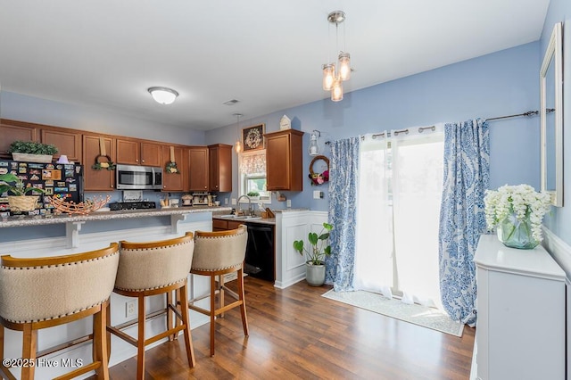 kitchen featuring stainless steel microwave, refrigerator, dishwasher, light countertops, and a kitchen breakfast bar