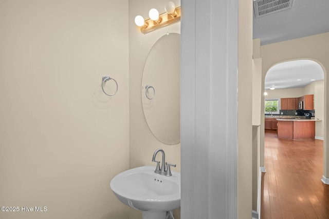 323 Frisco Way, Holly Ridge, NC 28445 - bathroom featuring a sink, wood finished floors, and decorative backsplash