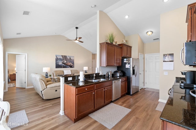 kitchen featuring stainless steel appliances, a sink, open floor plan, high vaulted ceiling, and a ceiling fan