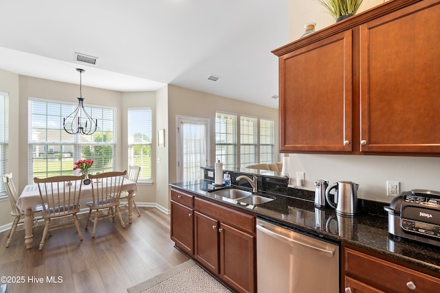 kitchen featuring dishwasher, a sink, wood finished floors, baseboards, and hanging light fixtures