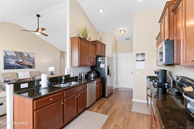 kitchen featuring appliances with stainless steel finishes, a sink, vaulted ceiling, a ceiling fan, and a peninsula