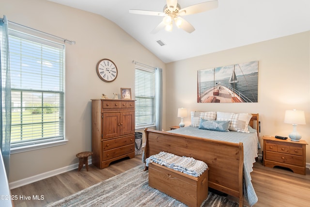 bedroom featuring light wood finished floors, vaulted ceiling, multiple windows, baseboards, and ceiling fan