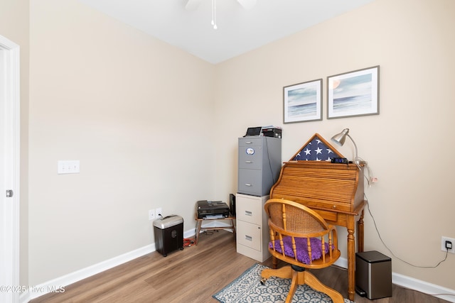 home office featuring light wood finished floors, a ceiling fan, and baseboards