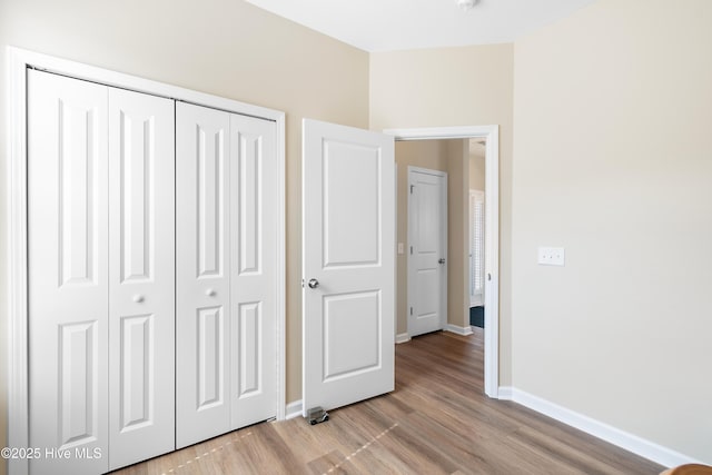 unfurnished bedroom with light wood-style floors, a closet, and baseboards