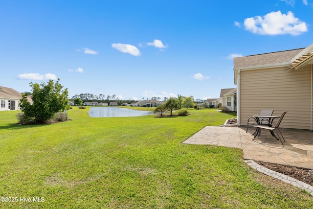 view of grassy yard with a patio area, a water view, and a residential view