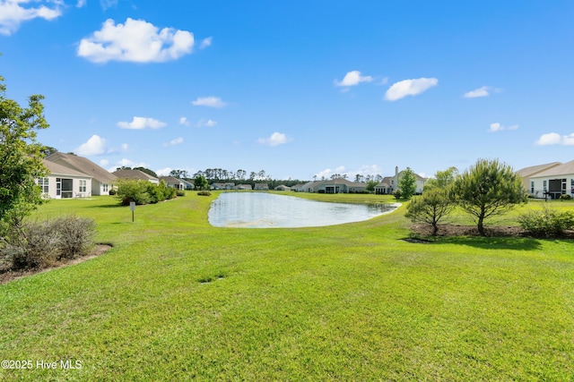 view of grassy yard with a residential view and a water view