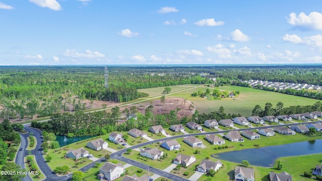 aerial view of property's location featuring nearby suburban area, a forest, and a nearby body of water