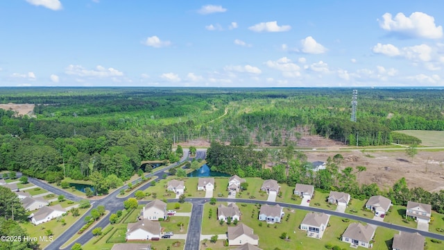 aerial view of property and surrounding area featuring a forest and nearby suburban area