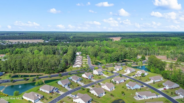 aerial view of property and surrounding area with a heavily wooded area, a large body of water, and nearby suburban area
