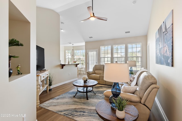 living area with baseboards, lofted ceiling, wood finished floors, and ceiling fan