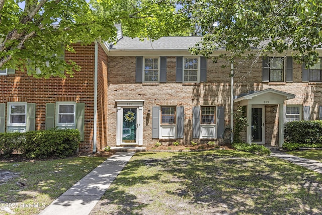 view of property with brick siding and a front yard