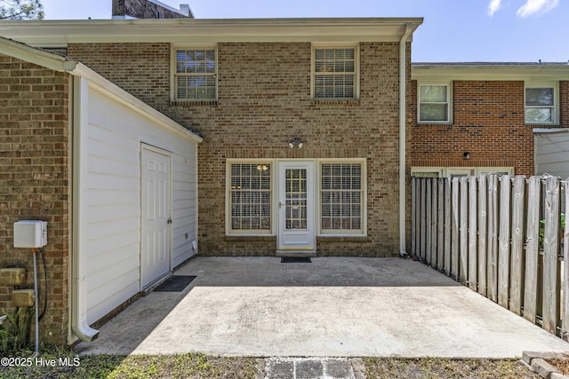 rear view of property with a patio area, fence, and brick siding