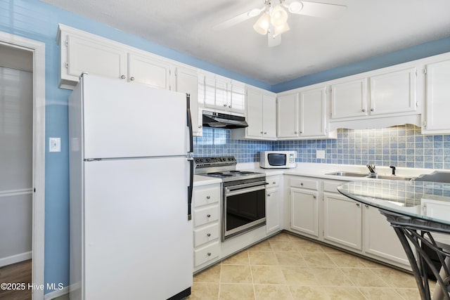 kitchen featuring under cabinet range hood, white appliances, a sink, backsplash, and white cabinets