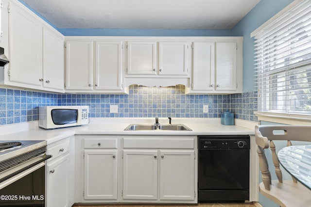 kitchen with black dishwasher, white microwave, white cabinets, and a sink