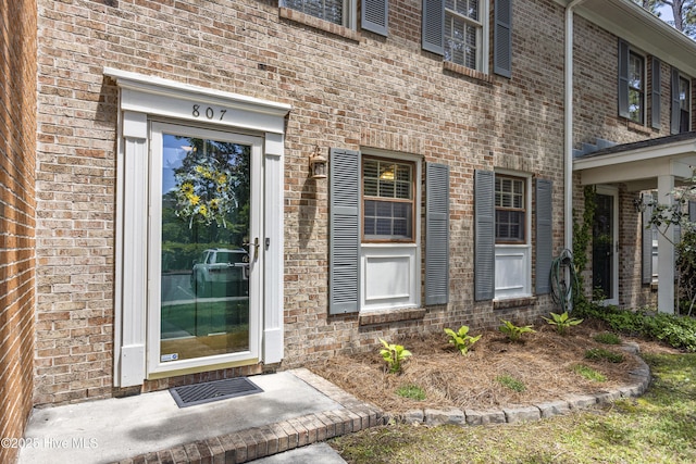 doorway to property featuring brick siding