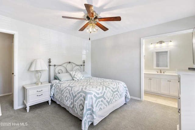 bedroom with a ceiling fan, a sink, ensuite bathroom, baseboards, and light carpet