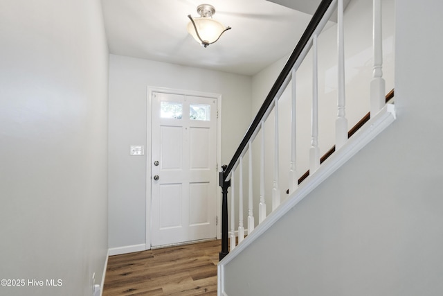 foyer featuring wood finished floors, baseboards, and stairs