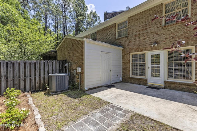 exterior space featuring central AC unit, a patio, brick siding, and fence