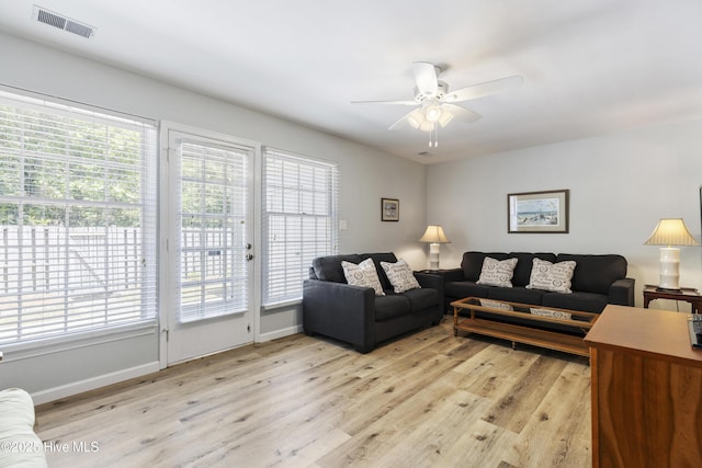 living area with light wood-type flooring, visible vents, baseboards, and ceiling fan