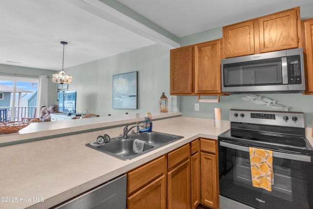 kitchen featuring stainless steel appliances, a sink, light countertops, decorative light fixtures, and a peninsula