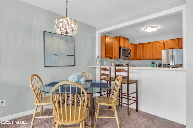dining room with light colored carpet, a chandelier, and baseboards