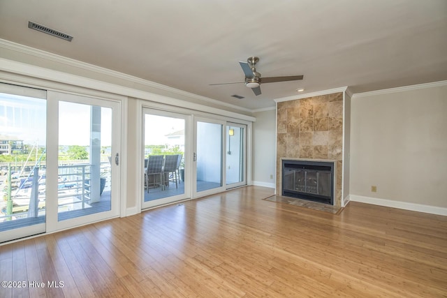 unfurnished living room featuring ornamental molding, baseboards, wood finished floors, a fireplace, and ceiling fan