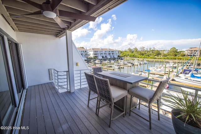 wooden deck featuring view of marina, ceiling fan, and a water view
