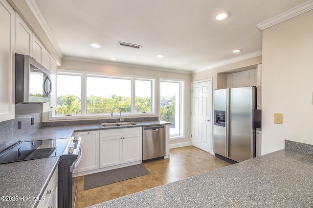 kitchen with stainless steel appliances, a sink, dark countertops, recessed lighting, and ornamental molding