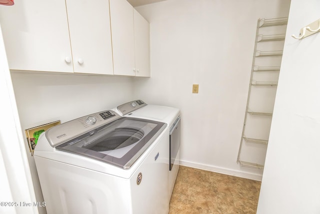 clothes washing area featuring washer and dryer, cabinet space, and baseboards