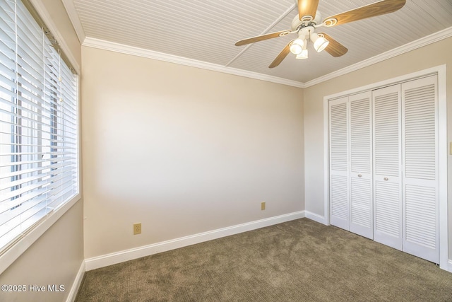 unfurnished bedroom with carpet floors, a closet, baseboards, ornamental molding, and a ceiling fan