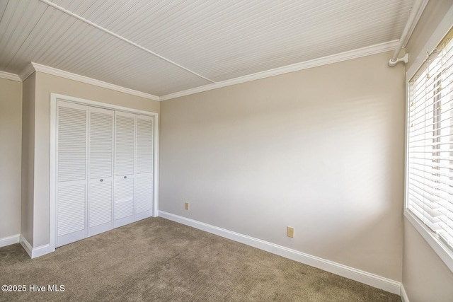 unfurnished bedroom featuring carpet, crown molding, a closet, and baseboards