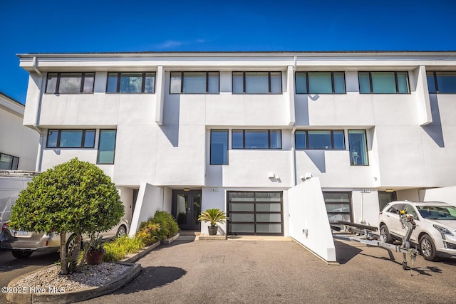 multi unit property featuring stucco siding, a garage, and driveway
