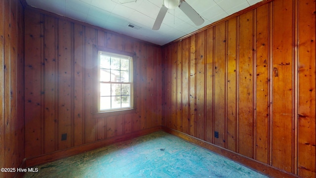 empty room with baseboards, tile patterned floors, wooden walls, and a ceiling fan