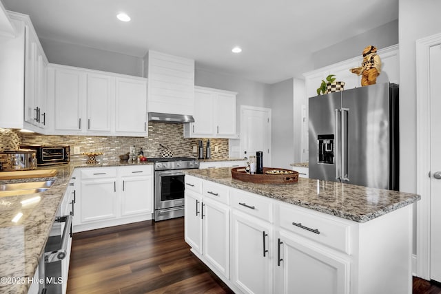 5606 Swiss Stone Ct, Wilmington, NC 28412 - kitchen with premium appliances, a kitchen island, range hood, backsplash, and white cabinetry
