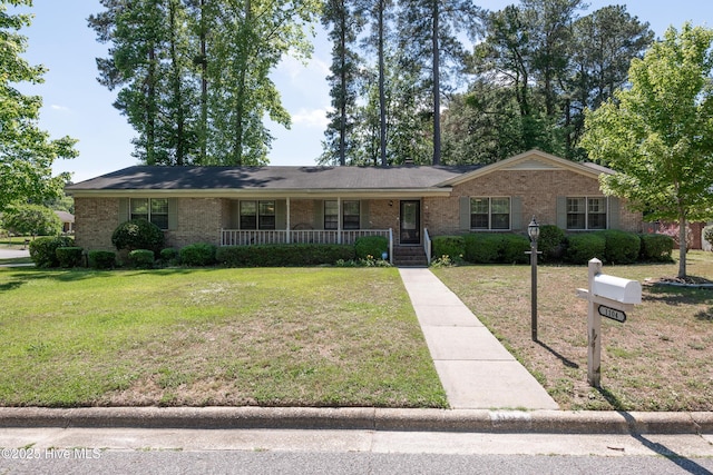 ranch-style home featuring covered porch, brick siding, and a front yard
