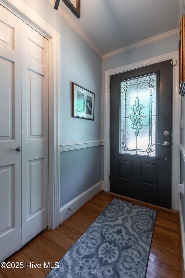 foyer entrance with ornamental molding, wood finished floors, and baseboards