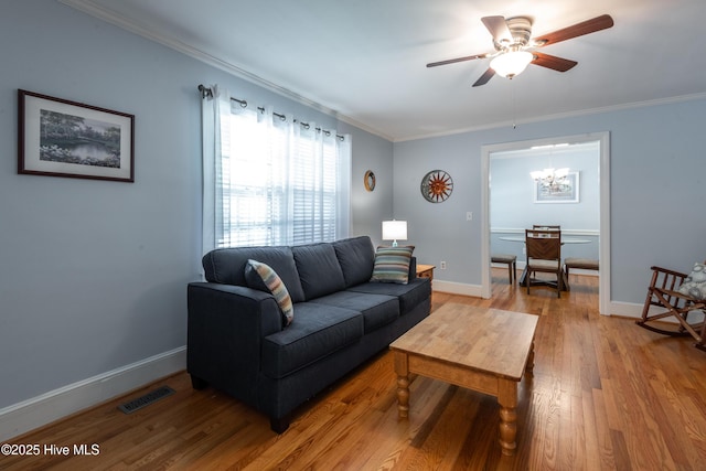 living room featuring a chandelier, light wood-type flooring, ceiling fan, crown molding, and baseboards