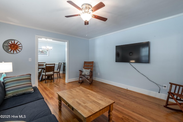 living area featuring light wood-style flooring, crown molding, a chandelier, ceiling fan, and baseboards