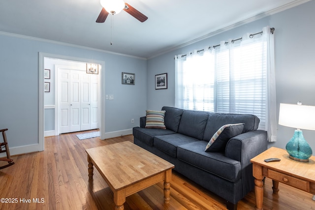 living area featuring ceiling fan, crown molding, baseboards, and wood finished floors