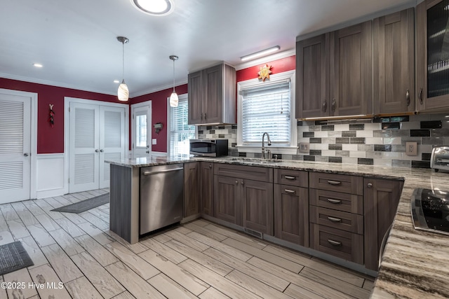 kitchen with appliances with stainless steel finishes, a sink, a peninsula, tasteful backsplash, and wainscoting